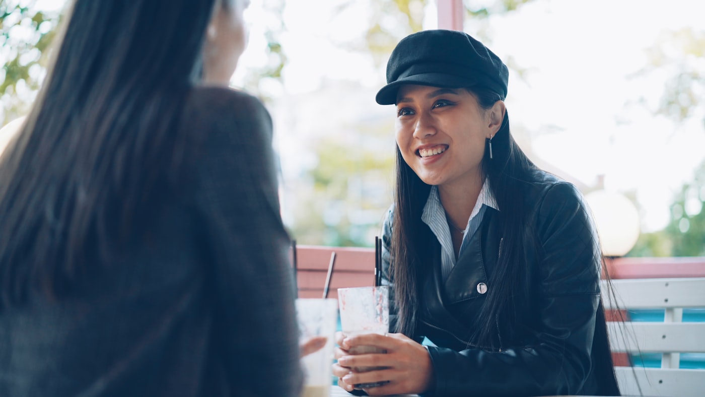 Two friends talking over drinks at a cafe