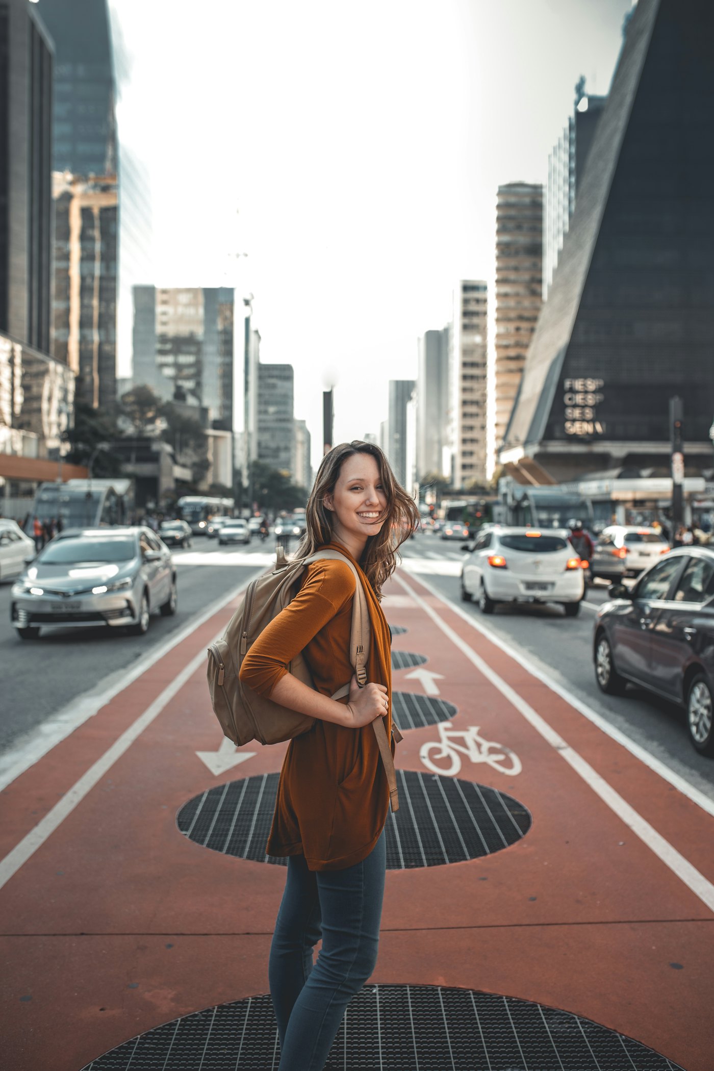 A woman with a backpack on a busy city avenue